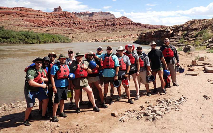 a group of veterans pose by a river on an outward bound trip